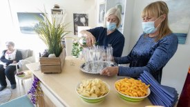 Två kvinnor som häller upp cider i champagneglas.