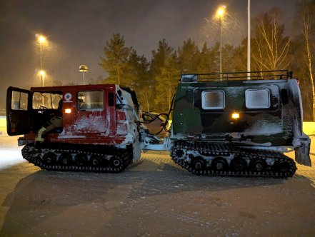 En grön och röd bandvagn står ute i snöoväder.