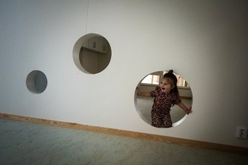 Ett barn tittar ut från ett hål i väggen.