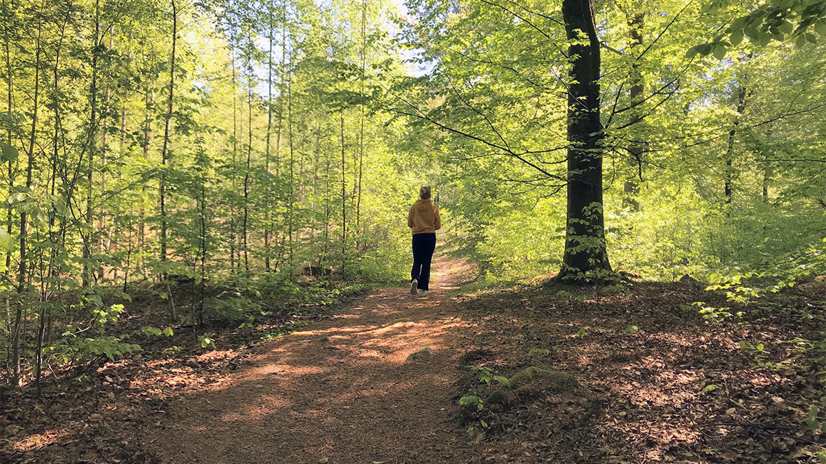 En kvinna som springer på ett spår i skogen.