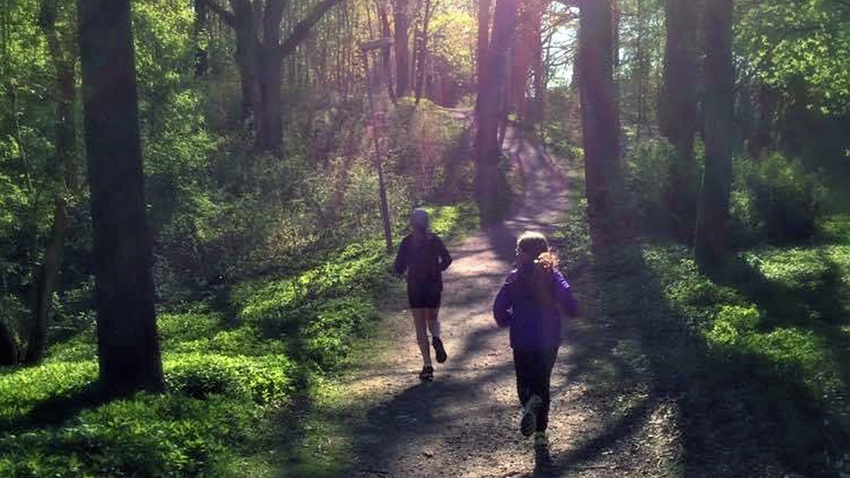 Två personer som springer på ett spår i skogen.