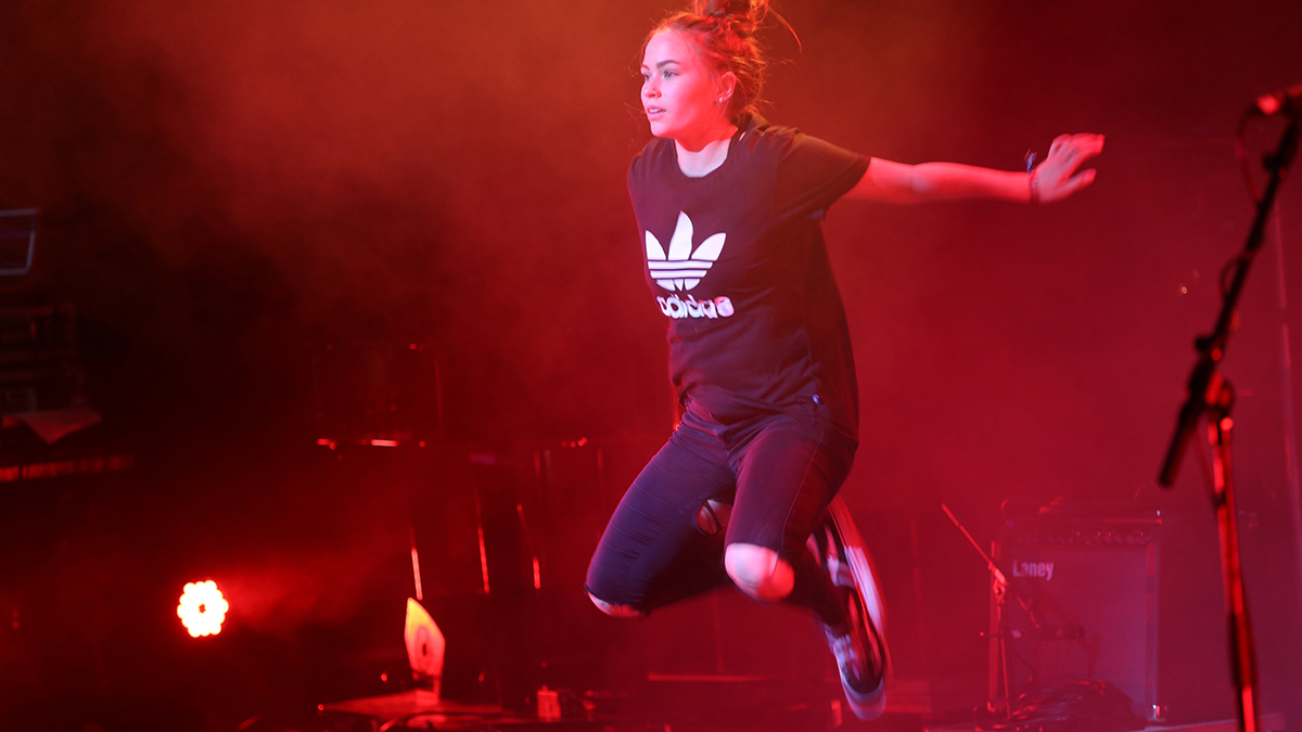 En tjej i svarta kläder hoppar på en scen